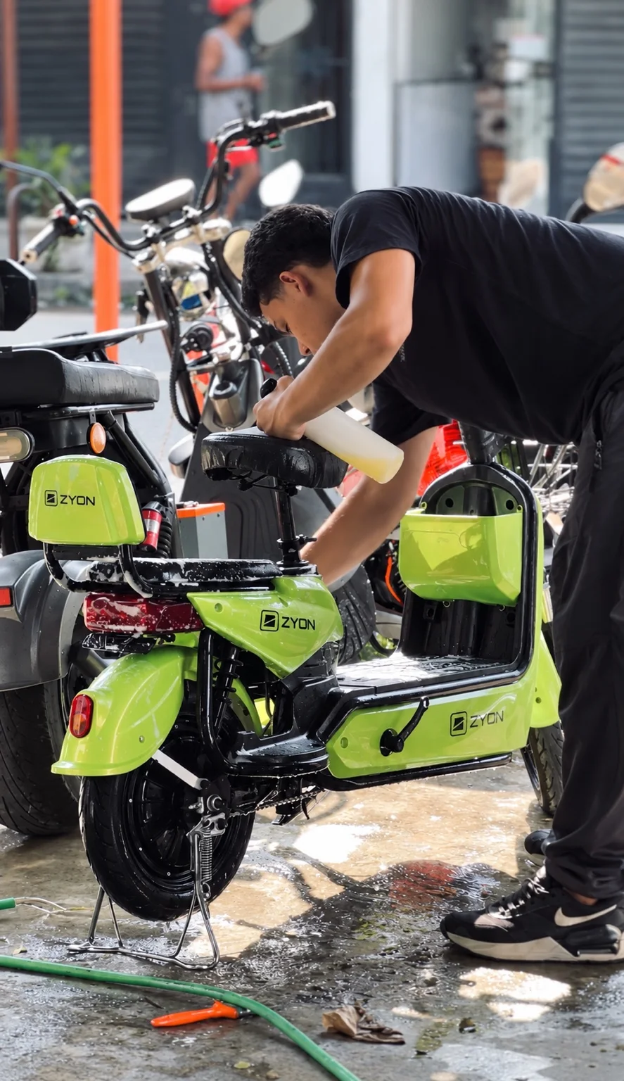 Profissional cuidando de uma scooter elétrica verde na ZEM
